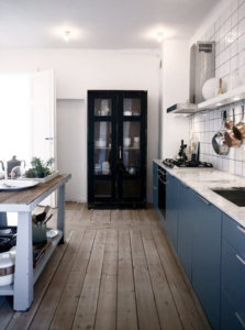 使い込まれた古い床材にブルーのキッチンが映えるビンテージとモダンが融合したミックススタイルのインテリア事例
